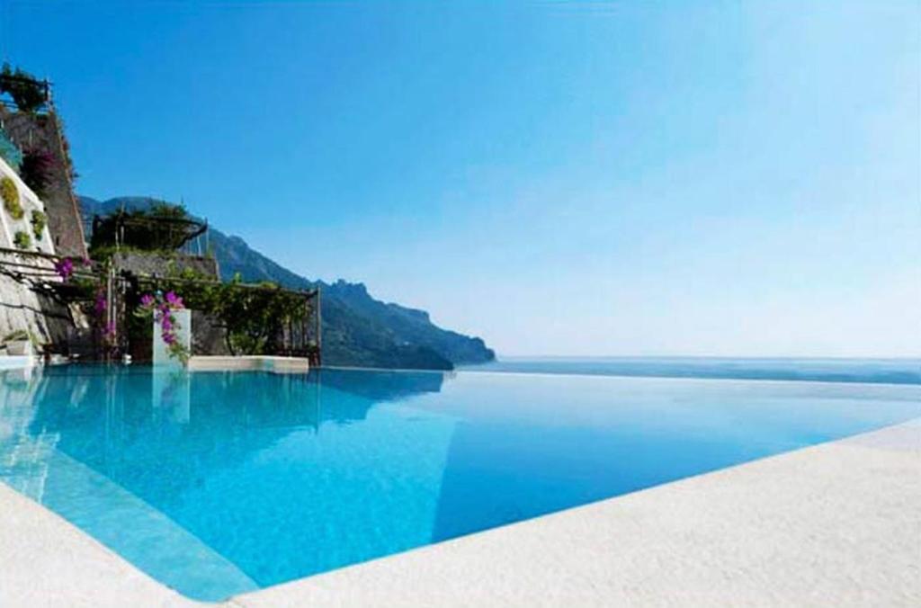 una grande piscina di acqua blu accanto all'oceano di Pagliarulo Complex by AMALFIVACATION a Ravello