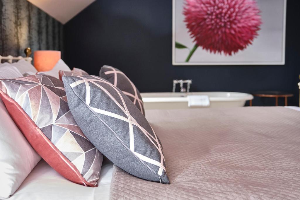 a bedroom with a bed with pillows and a bath tub at The Westleton Crown in Westleton