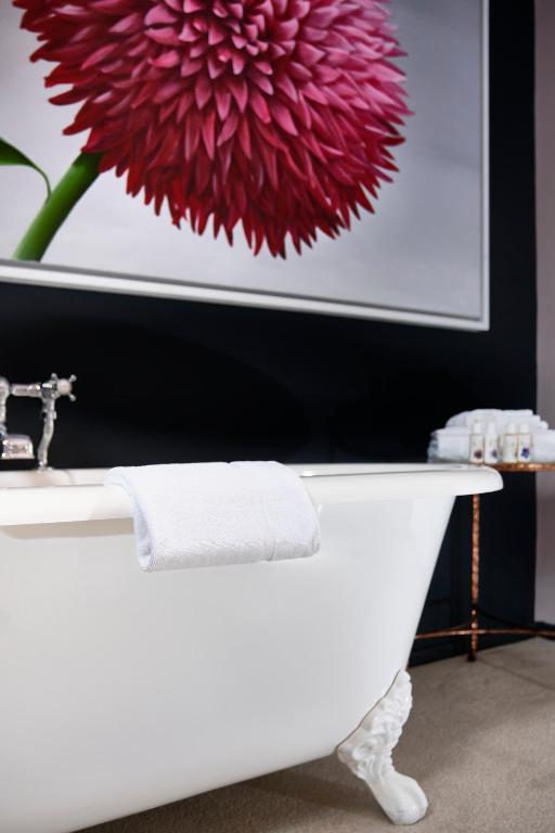 a white bath tub with a large red flower on the wall at The Westleton Crown in Westleton