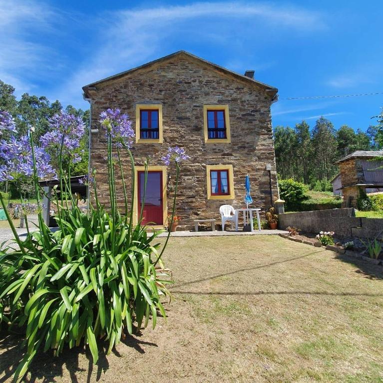 a stone house with purple flowers in front of it at Casa Rural O Rabadan in Cedeira