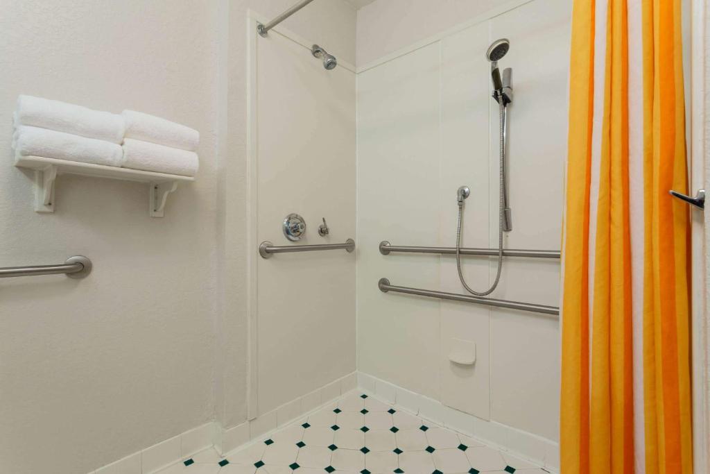 a bathroom with a shower with an orange shower curtain at La Quinta by Wyndham Lakeland West in Lakeland