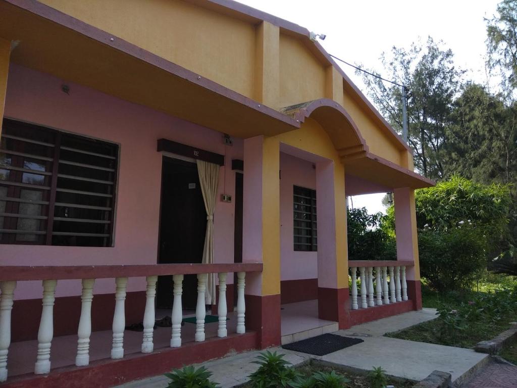 a small house with a yellow and pink at Tarangamala Resort in Mandarmoni