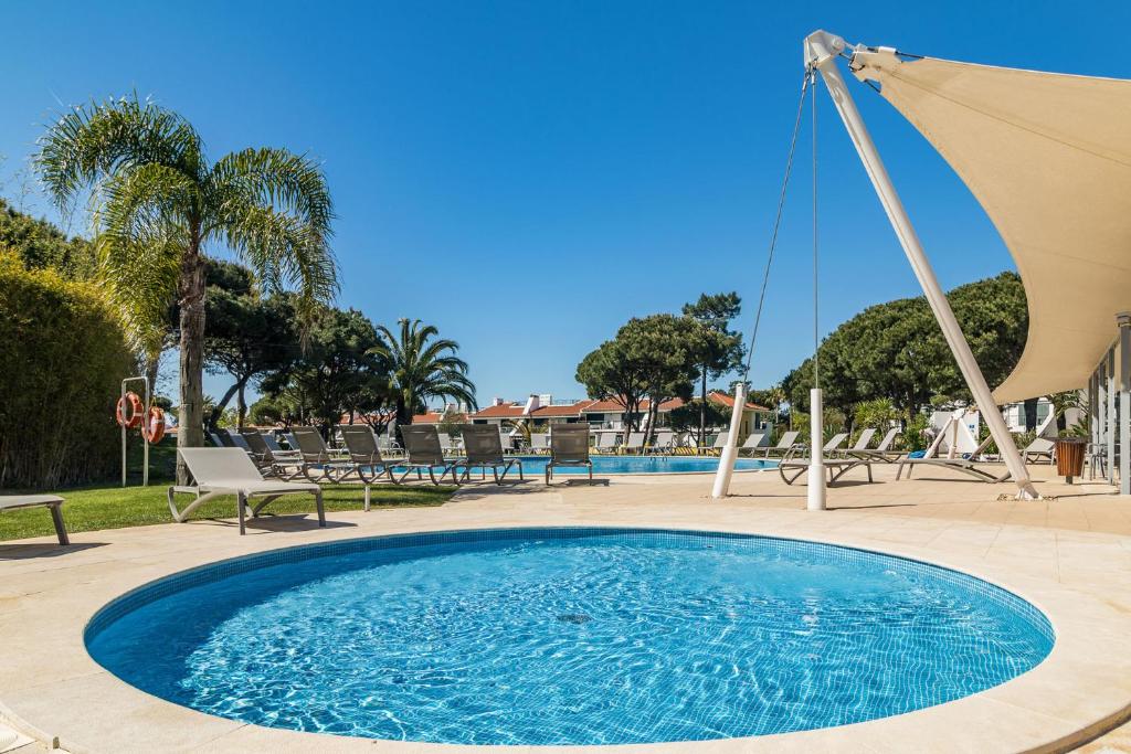 Vila Sol Resort 2 Bedroom Family Apartment في كوارتيرا: حمام سباحة أزرق كبير مع كراسي ومظلة