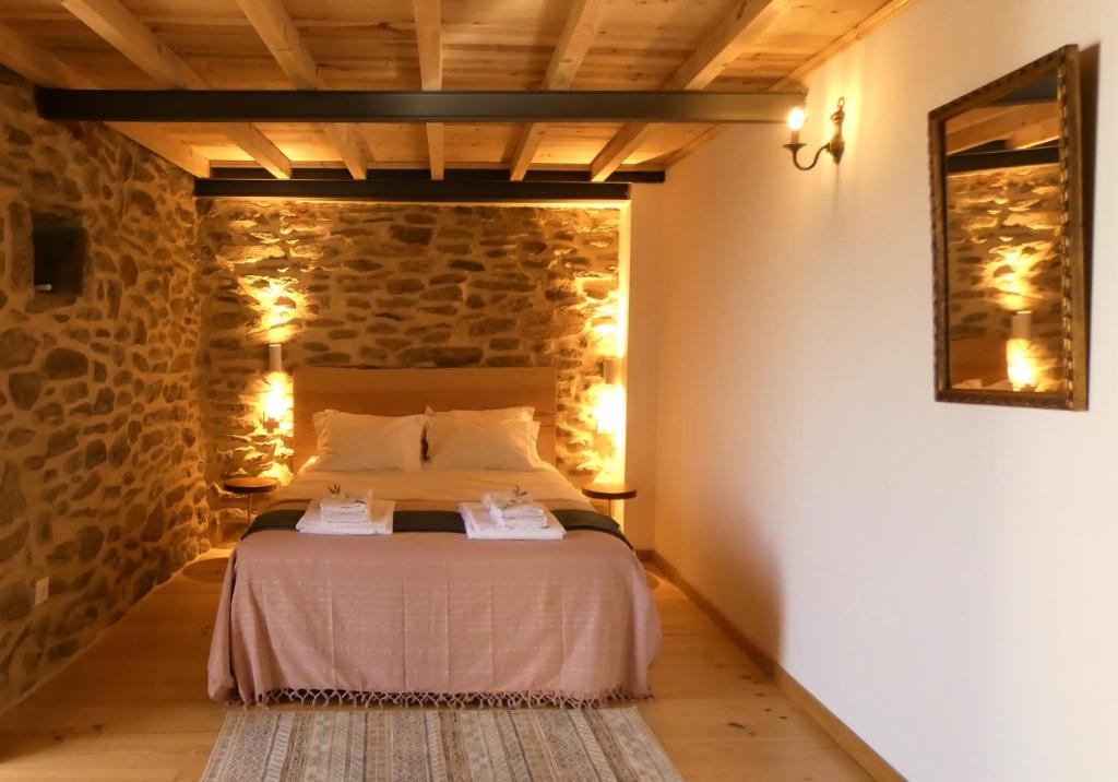 1 dormitorio con 1 cama en una pared de piedra en Casa da Laja - Casas de Villar- Rural Experience, en Vilar de Amargo