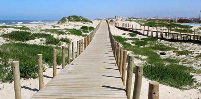 a wooden boardwalk on the beach near the ocean at Hotel Monte Lírio in Espinho