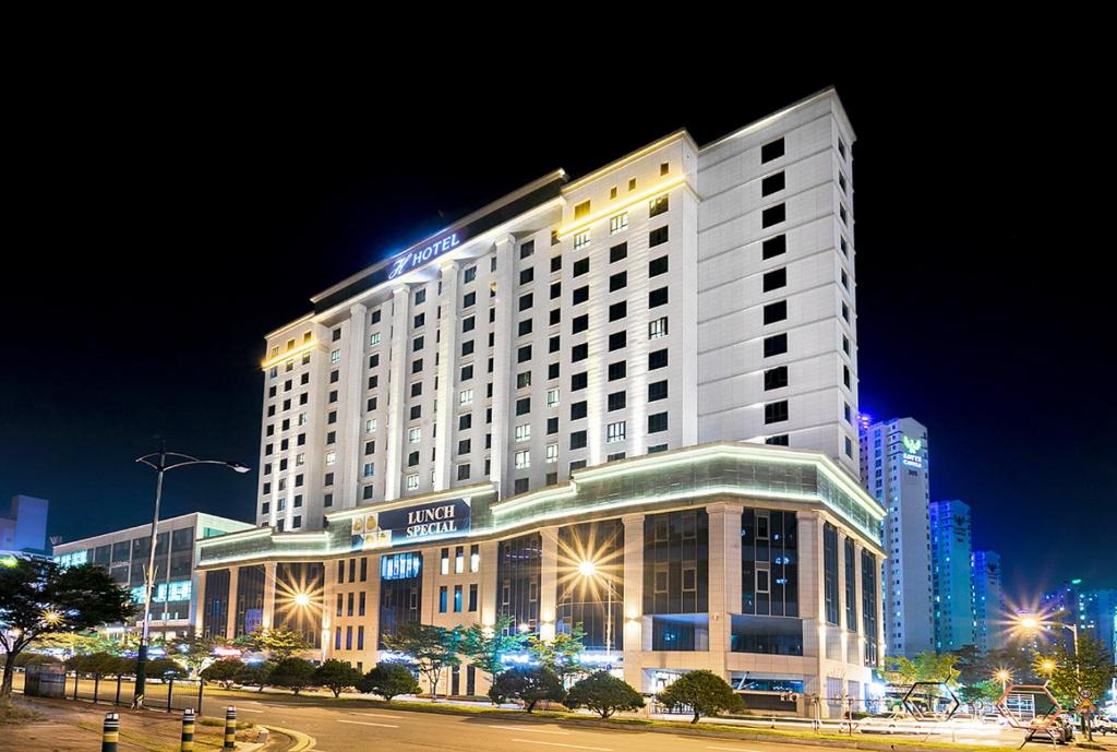 a lit up hotel building at night at Osong H Hotel Sejong City in Cheongju