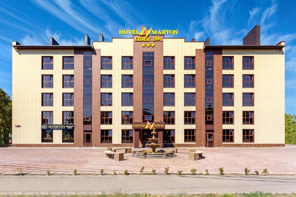 a hotel building with a fountain in front of it at Marton LIDER Krasnodar in Krasnodar