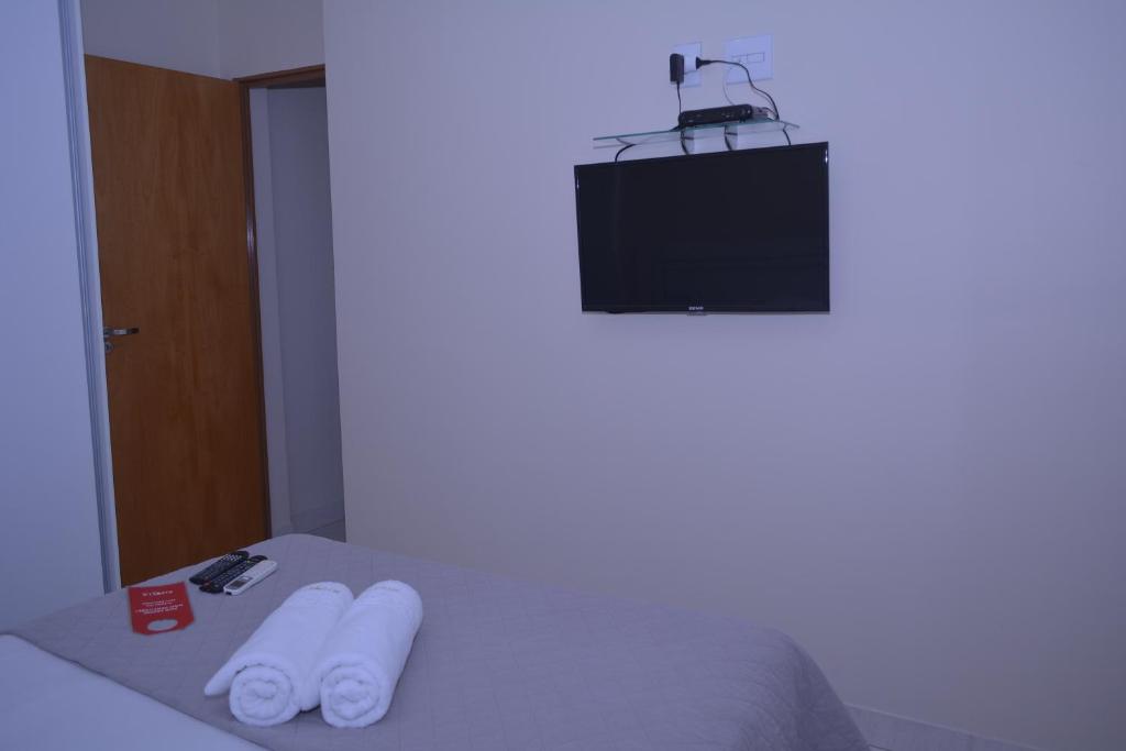 a room with a bed with a television and two towels at Rivello Apart Hotel in Sete Lagoas