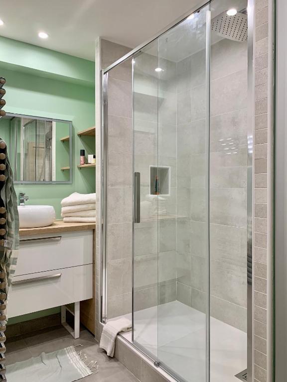 a glass shower in a bathroom with green walls at LE TROIS B in Beaune