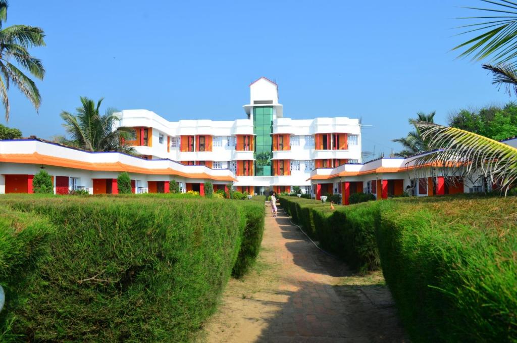 a building with red and whitefacades and green hedges at Neel Nirjaney Resorts in Mandarmoni