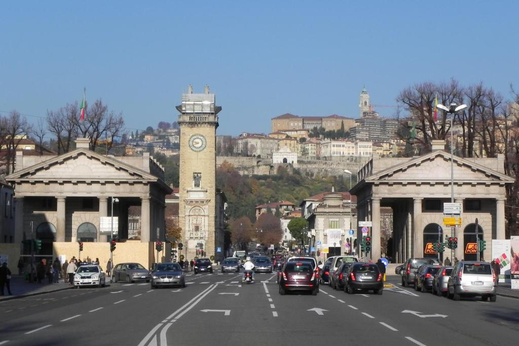 uma movimentada rua da cidade com uma torre de relógio e carros em Appartamento Monet em Bérgamo