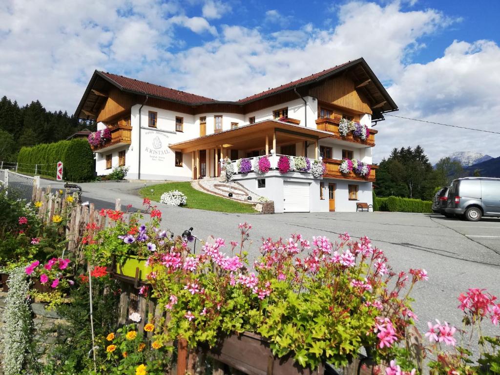 a house with flowers in front of it at Hotel Pension Appartement Kristall in Tröpolach