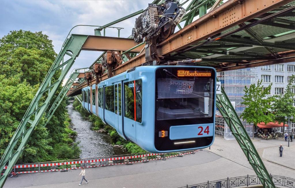 a blue train on a bridge over a river at Fewo Wuppertal in Wuppertal