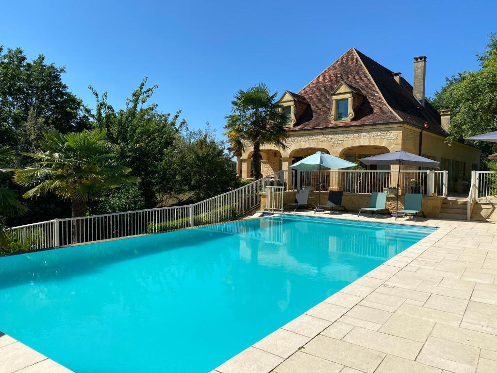 a swimming pool in front of a house at Hôtel Bon Encontre in Sarlat-la-Canéda