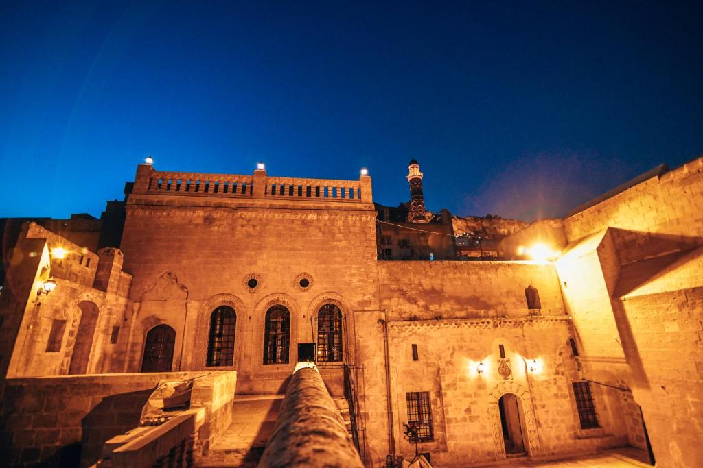 un edificio antiguo con una torre de reloj en el fondo en Maristan Tarihi Konak en Mardin