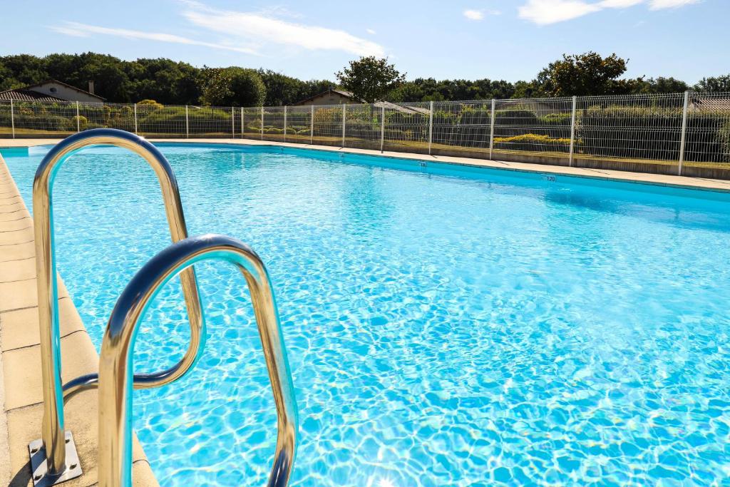 a swimming pool with blue water and metal rails at French country home III in Les Forges