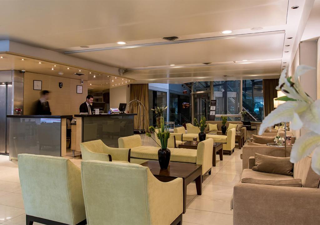 a lobby with chairs and tables and a man in a bar at Hotel Solans Presidente in Rosario