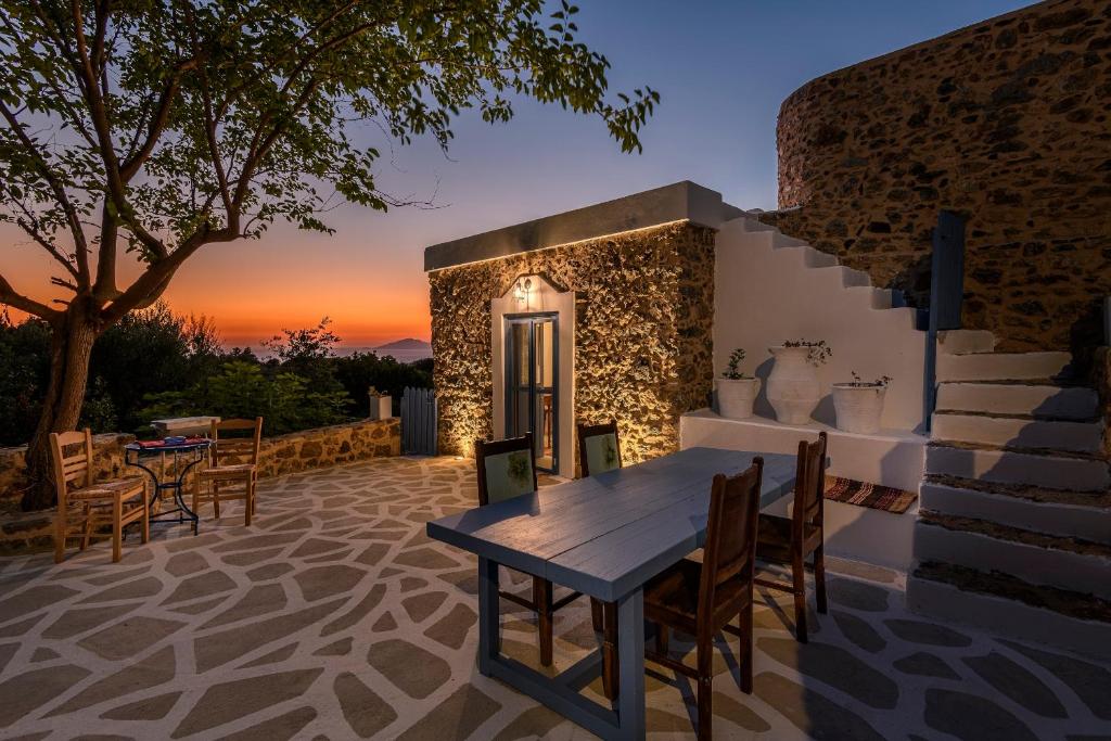 eine Terrasse mit einem Tisch und Stühlen bei Sonnenuntergang in der Unterkunft The Aegean blue country house Old Milos in Lagoúdi Zía