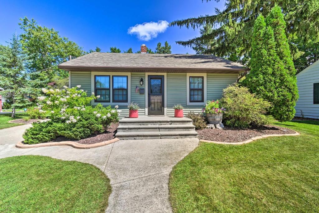 a green house with a porch with plants at Modern Home with Backyard, 1 Mi to Dtwn Sturgeon Bay in Sturgeon Bay