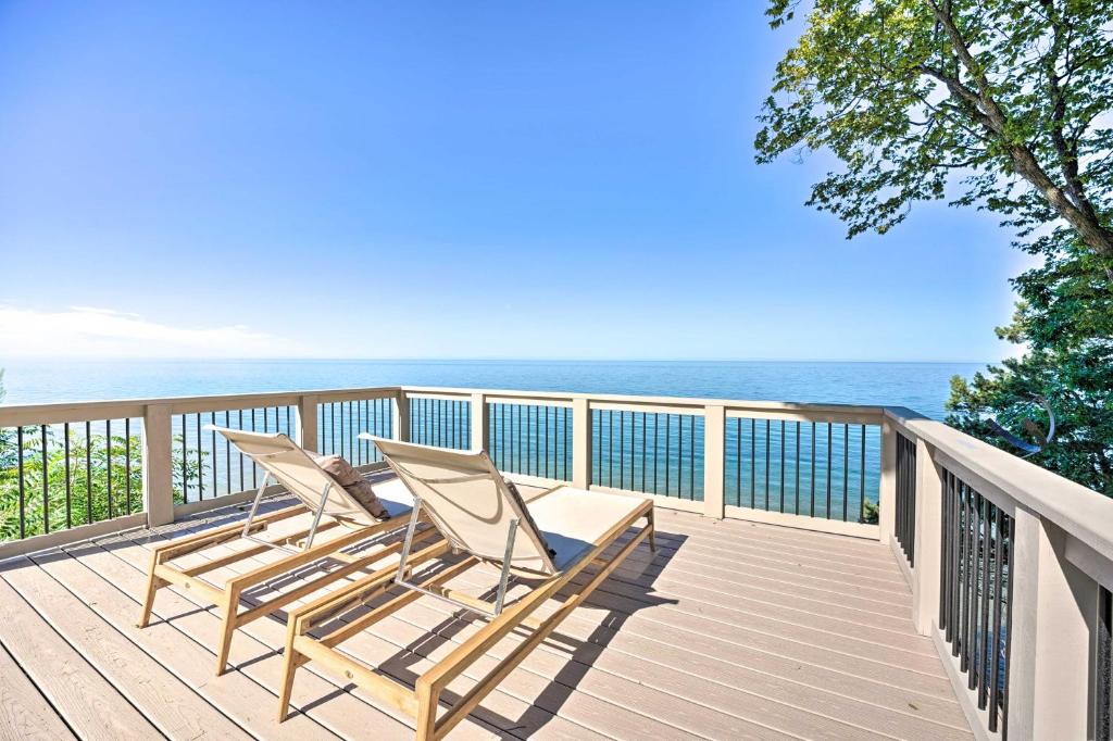 two chairs sitting on a deck overlooking the ocean at Modern Lake Michigan Home with 3 Lakefront Decks! in Holland
