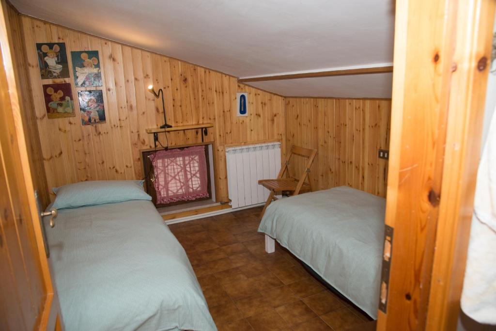 Cette petite chambre comprend deux lits et une chaise. dans l'établissement Appartamento Le Betulle, à Erbezzo