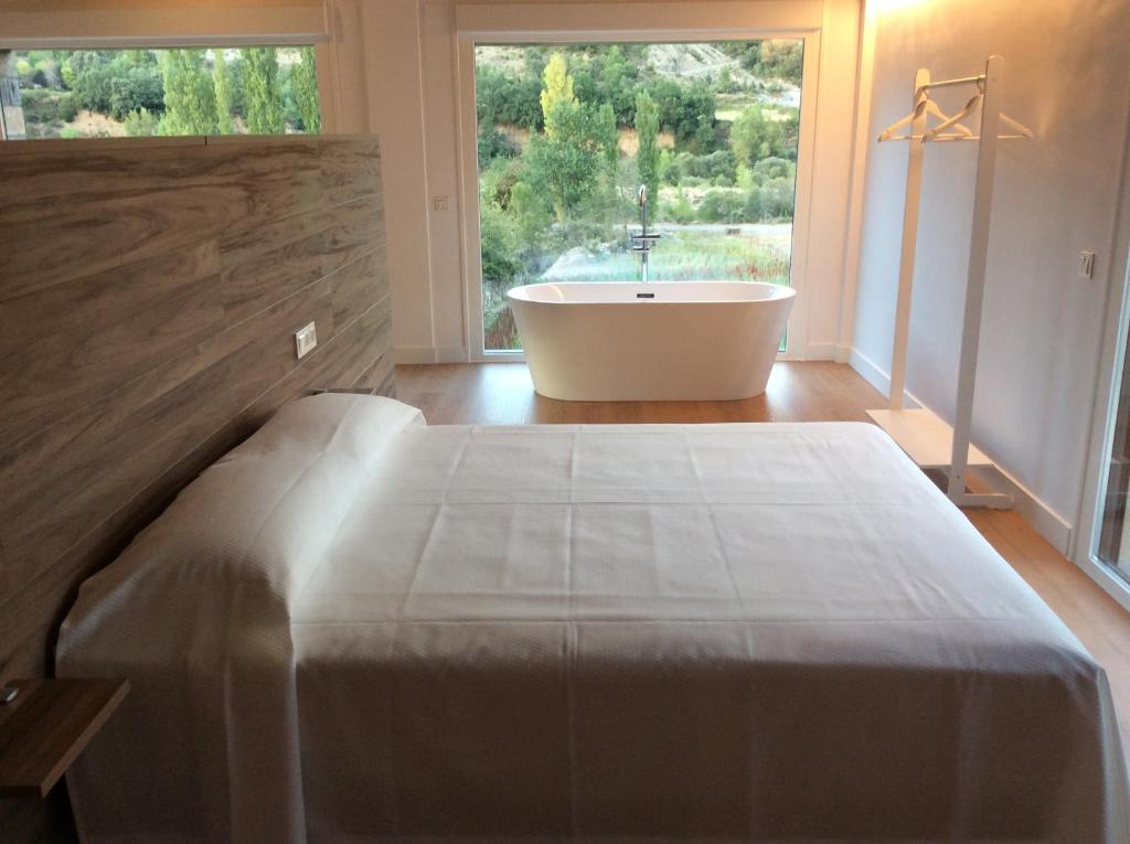 1 dormitorio con bañera, cama y ventana en Huertas de Muro Turismo Rural, en Escalona
