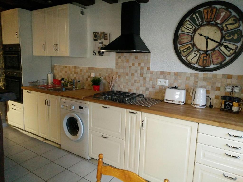 eine Küche mit einer Uhr an der Wand und einer Waschmaschine in der Unterkunft Le Pigeonnier, maison de charme au pied du château in Amboise