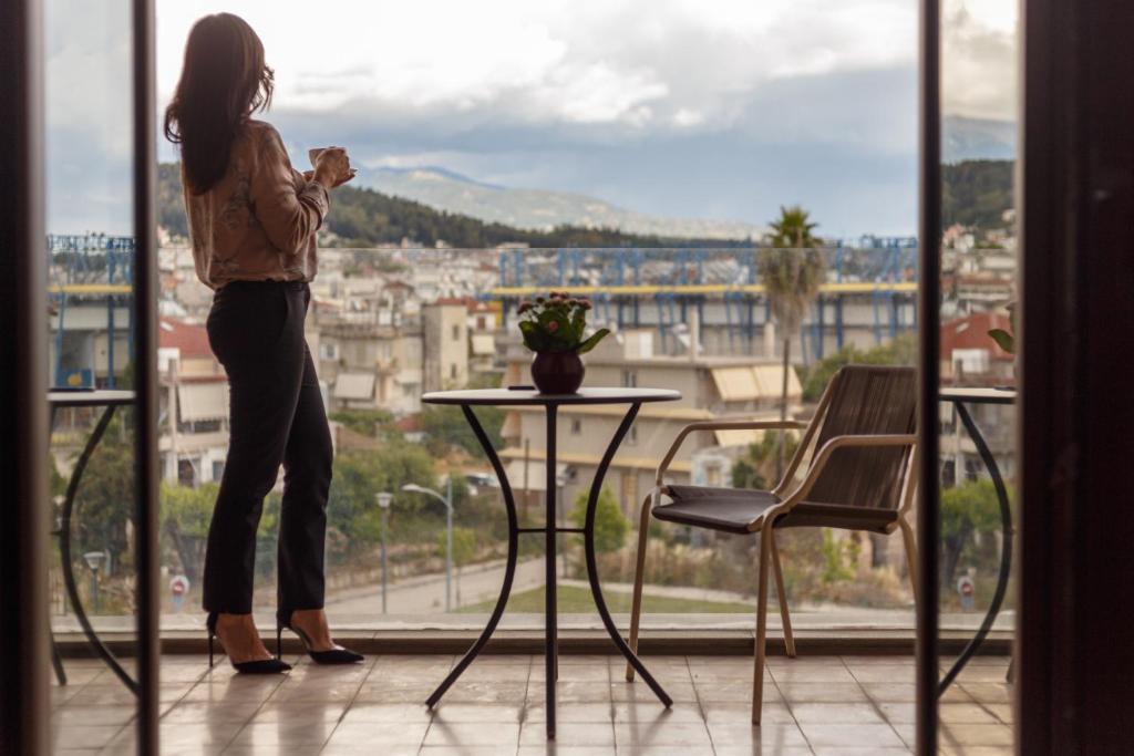 a woman standing on a balcony looking out at the city at Marpessa Hotel & Spa in Agrinion