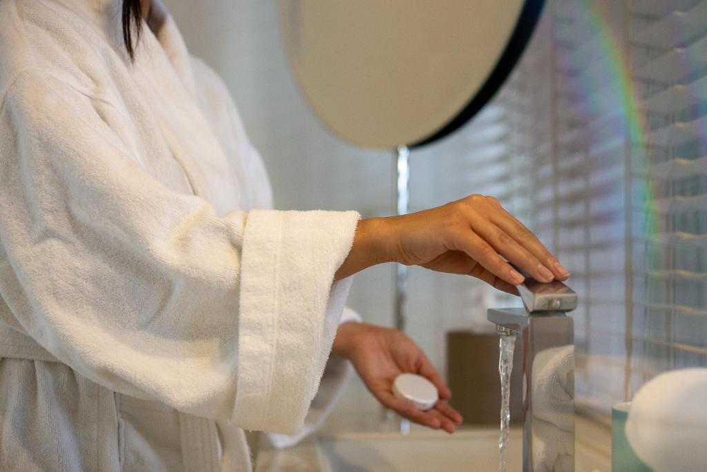 a woman in a white towel is washing her hands at Marpessa Hotel & Spa in Agrinion