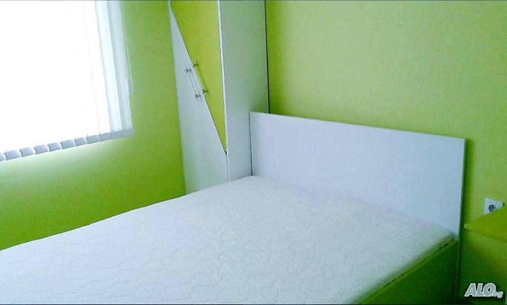 a white bed in a green room with a window at АПАРТАМЕНТ LEO 4 in Varna City