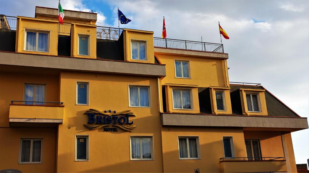 a yellow building with flags on top of it at Hotel Bristol in Enna