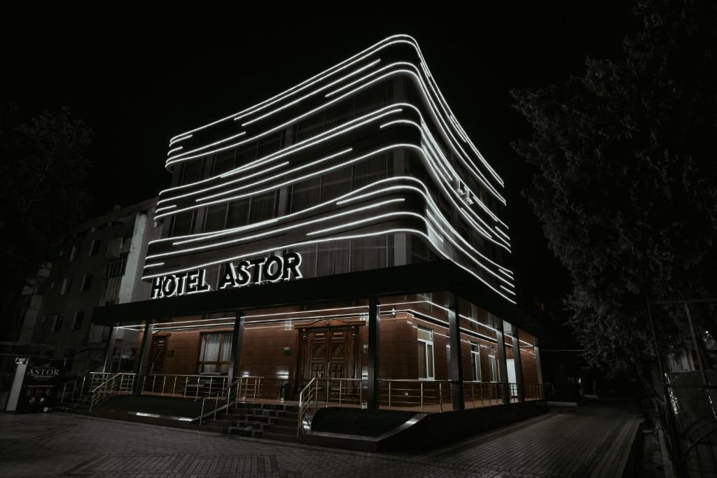 un edificio con una aseguradora del hotel iluminada por la noche en Astor Hotel, en Samarkand