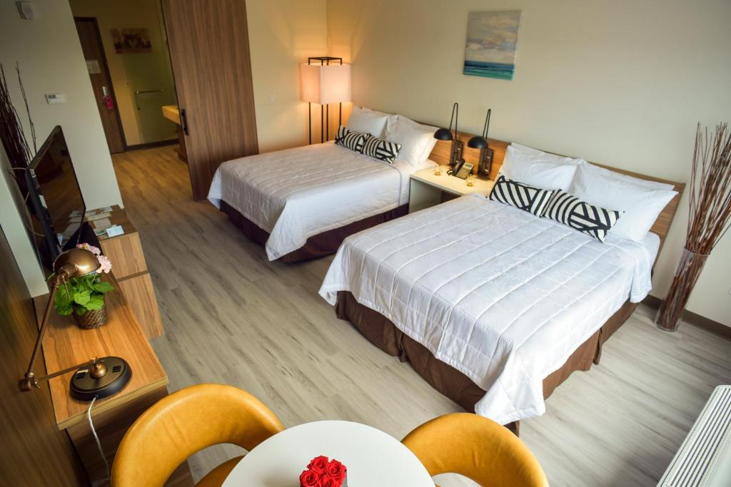 a hotel room with two beds and a table and chairs at Wyndham Garden North Bergen - Secaucus in North Bergen