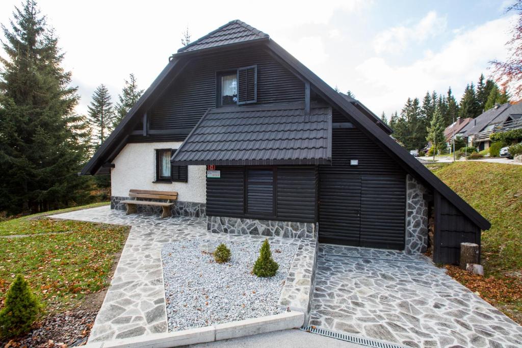 a black and white house with a bench in front of it at Rogla Chalet Urska in Resnik