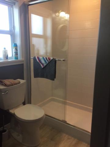 a bathroom with a toilet and a glass shower at Money Pennies Bed and Breakfast in Campbell River