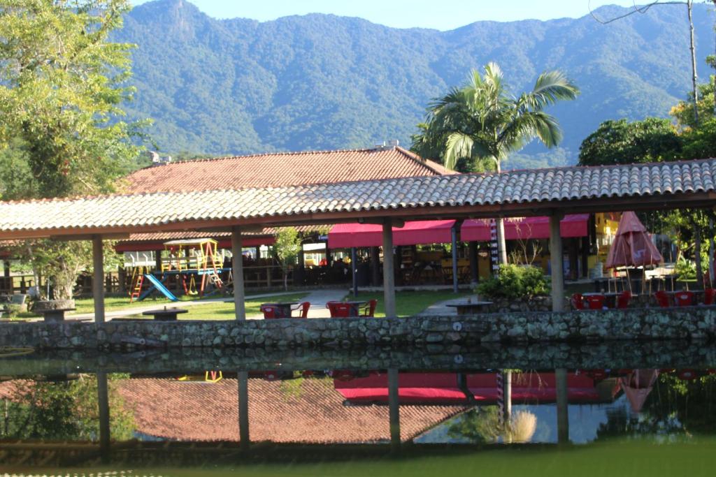 a resort with a table and chairs and mountains in the background at Pousada Rancho Texas Ubatuba in Ubatuba