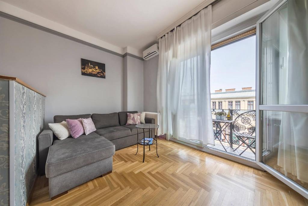 a living room with a couch and a large window at Astoria Balcony Apartment in Budapest