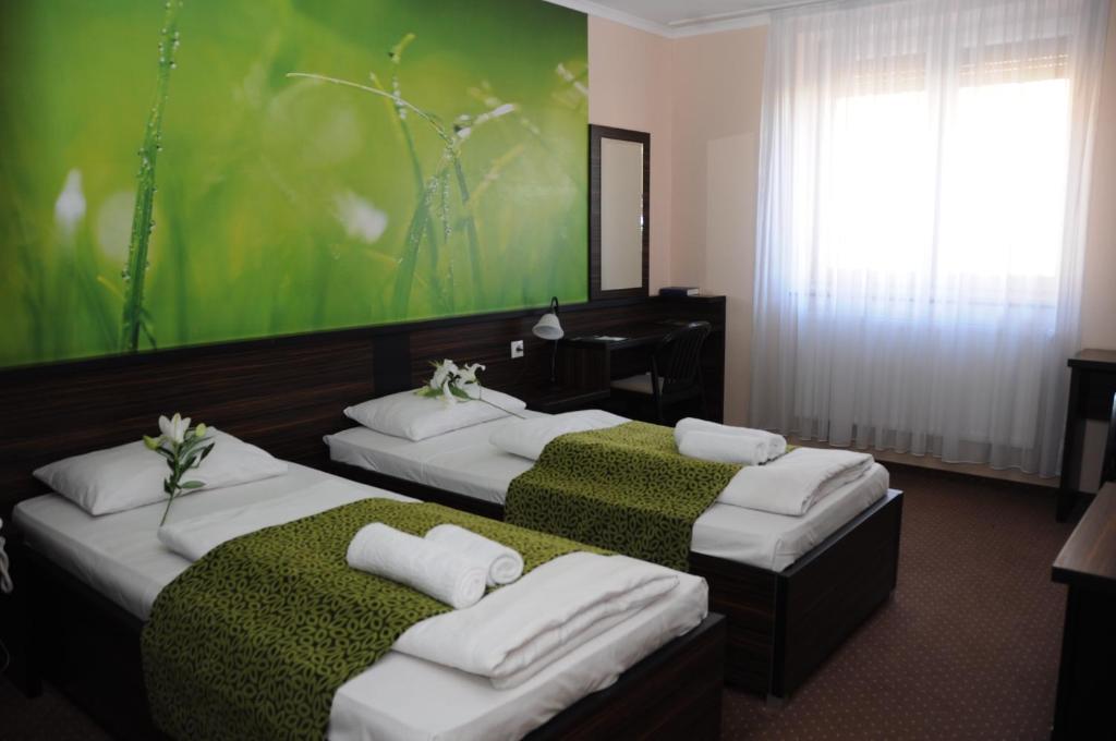 two beds in a hotel room with a green wall at Green Hotel Budapest in Budapest