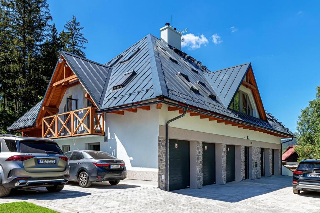 dom z metalowym dachem i samochodami zaparkowanymi na parkingu w obiekcie Apartmán B Harrachov w mieście Harrachov