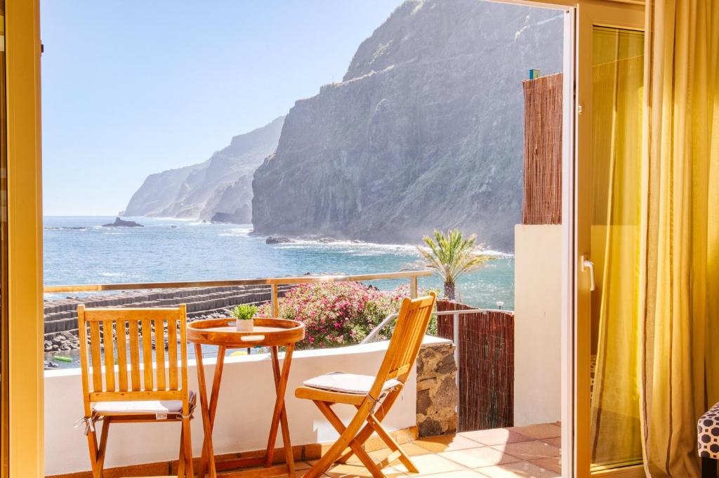 einen Balkon mit einem Tisch, Stühlen und Meerblick in der Unterkunft Madeira Offline - Ponta Delgada in Ponta Delgada