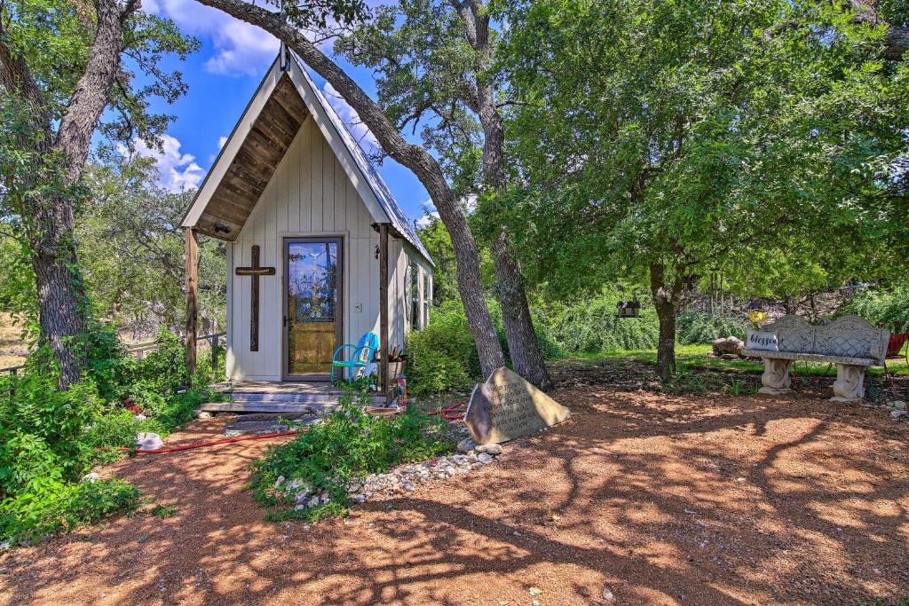 una pequeña casa blanca con un árbol y un banco en Cozy Texas Retreat with Patio, Grill and Fire Pit!, en Mountain Home