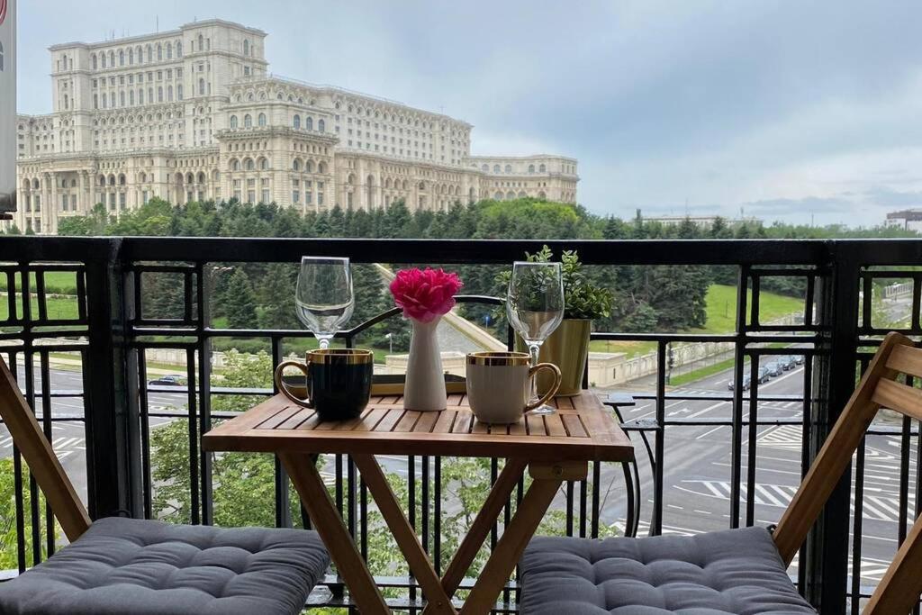 a wooden table with glasses and flowers on a balcony at New Luxury Flat in front of the Parliament at Unirii in Bucharest