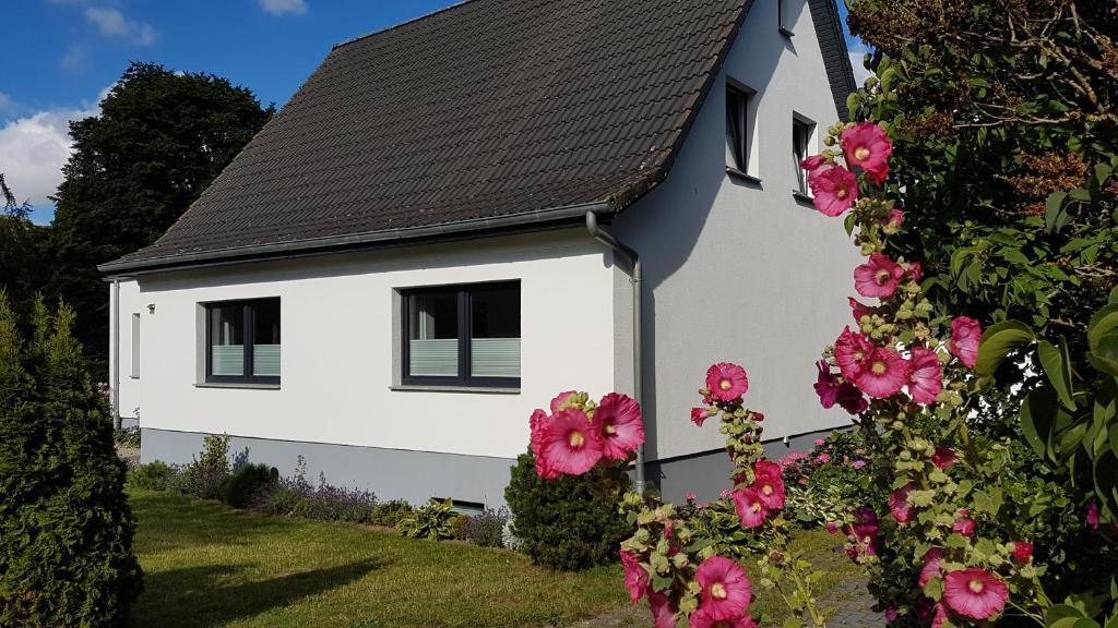 una casa blanca con flores rosas delante en Ferienhaus Meeresrauschen, en Binz