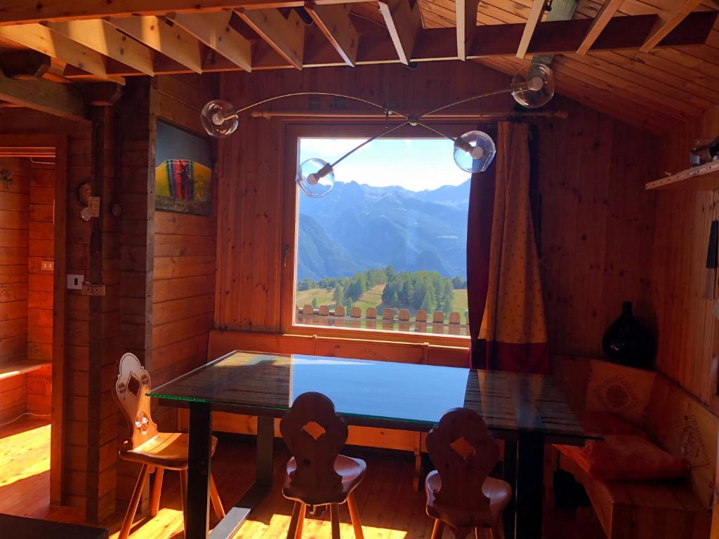 ein Esszimmer mit einem Tisch und einem großen Fenster in der Unterkunft Chalet Mondjoin in Torgnon