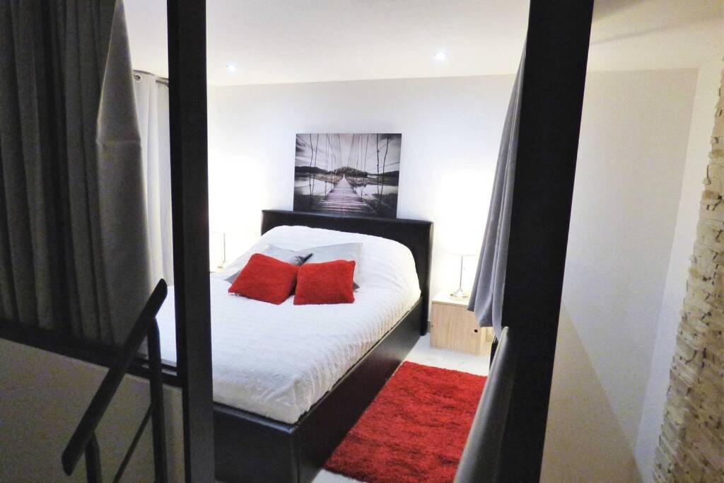 Un dormitorio con una cama con almohadas rojas. en Charmant Duplex Centre Historique Vitré, en Vitré