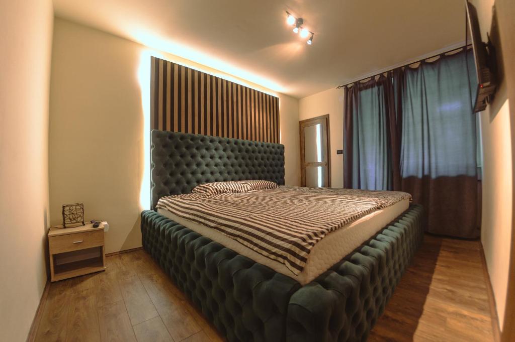ein Schlafzimmer mit einem großen Bett mit einem großen Kopfteil in der Unterkunft Loft Apartman Menhetn in Šabac