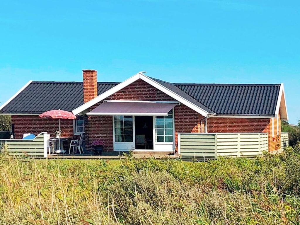 una casa de ladrillo rojo con porche y sombrilla en 6 person holiday home in R m en Lakolk