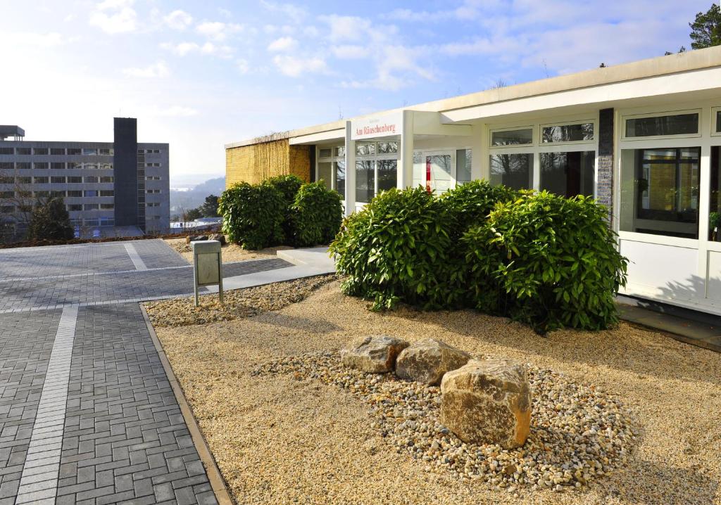 un edificio con arbustos y rocas delante de él en Gästehaus am Räuschenberg, en Höxter