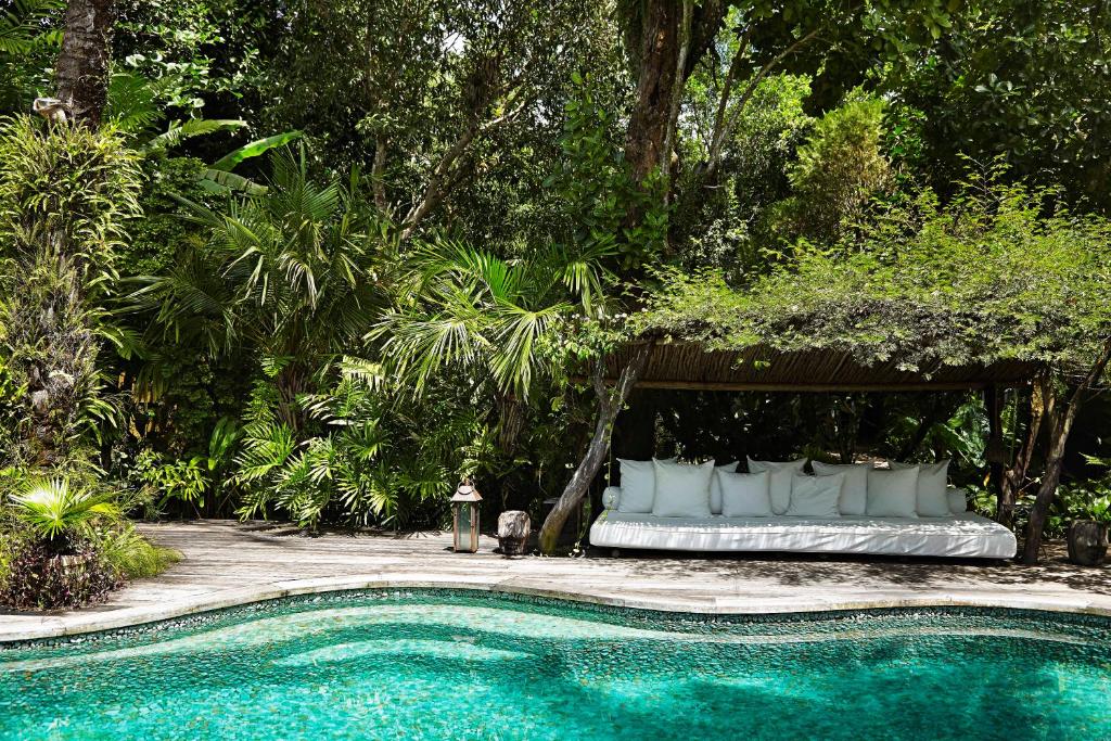 a bed sitting under a gazebo next to a swimming pool at UXUA Casa Hotel & Spa in Trancoso