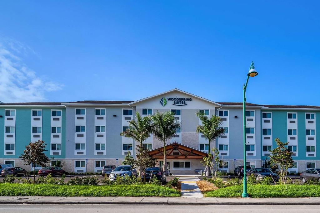 a large blue building with cars parked in a parking lot at WoodSpring Suites Naples West in Naples